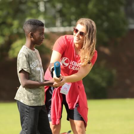 1x1_11 a red top helping a child with a rounders bat