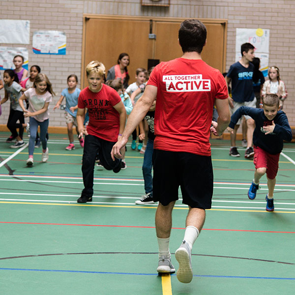 children and a red top running inside a sports hall