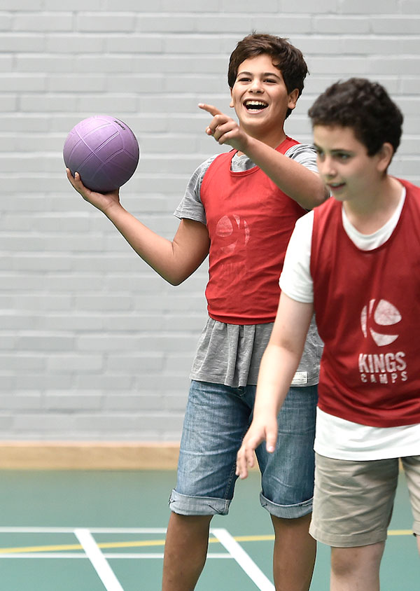 two children stood, one with a sports ball in his hand