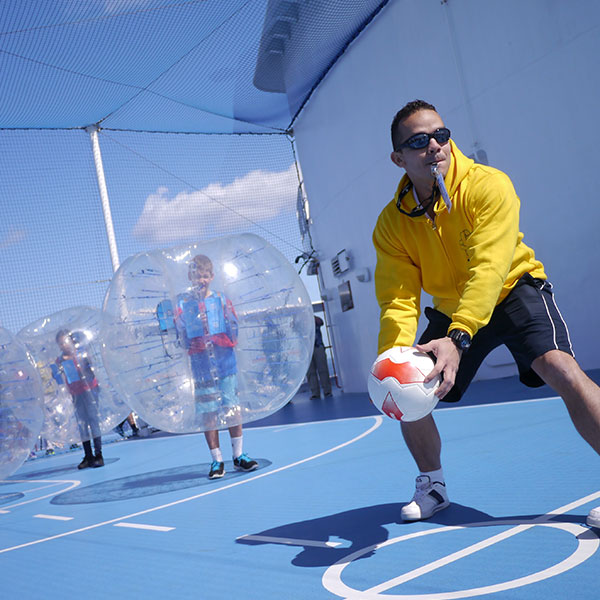 a sports coach with whistle in his mouth and ball in his hand