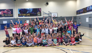 a large group of children and red tops with their hands in the air celebrating