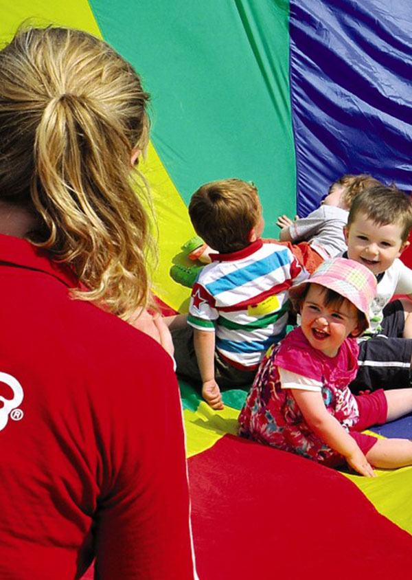 a group of small children playing parachute games