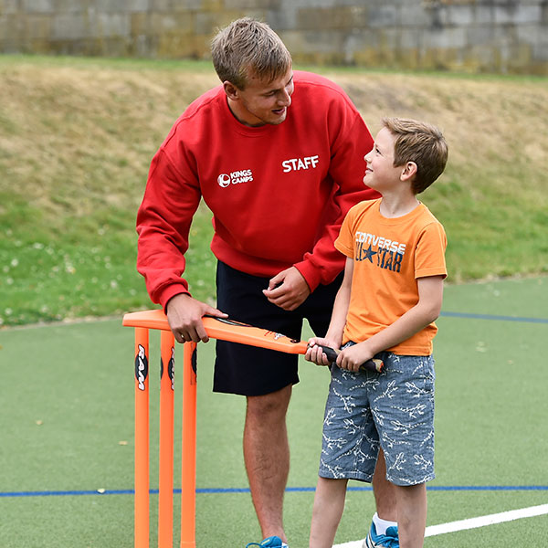 camps_007 a red top helping a child play ricket