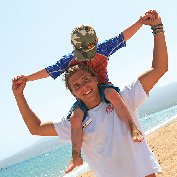 a child on a resort workers shoulders on the beach