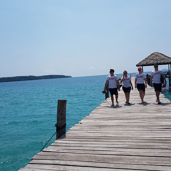 a group of staff walking on a board walk next to the sea