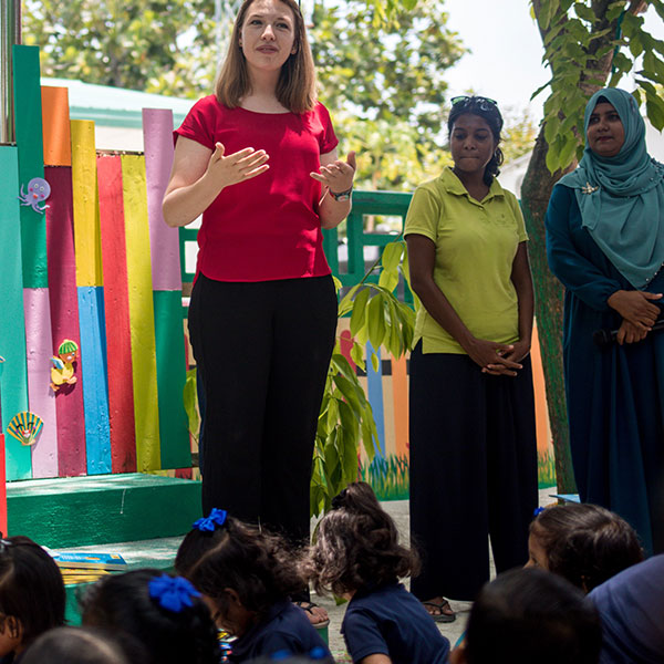 children's club manager stood up speaking to a group of children